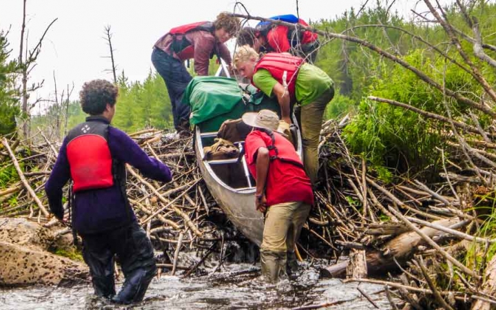 a group of students guide a canoe into the water on an outward bound course in minnesota 